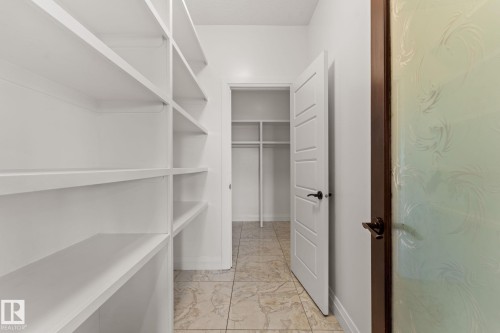 Integrated shelving units, tiled flooring, solid interior door with matte black hardware, and an additional closet space - 229 Albany Drive Nw, Edmonton, AB 