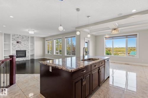 Kitchen island featuring a granite countertop, undermount sink, and stainless steel dishwasher - 229 Albany Drive Nw, Edmonton, AB 