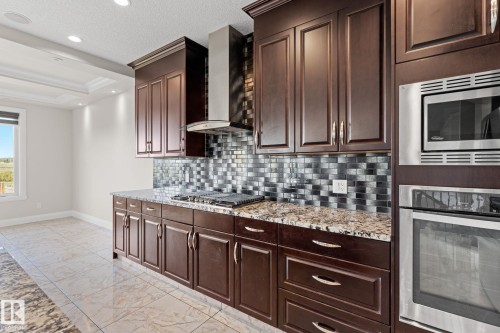 Dark wood-finish cabinetry, built-in stainless steel appliances, mosaic tile backsplash, polished stone countertops, and tile flooring - 229 Albany Drive Nw, Edmonton, AB 
