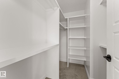 White built-in shelving, integrated hanging rod, and white paneled door with matte black hardware - 229 Albany Drive Nw, Edmonton, AB 
