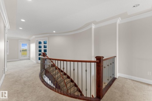 Curved staircase with wood-finish handrail and decorative metal balusters - 229 Albany Drive Nw, Edmonton, AB 