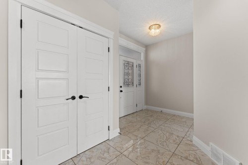 Entryway with patterned tile flooring, a decorative glass front door, and a crystal flush mount light fixture - 229 Albany Drive Nw, Edmonton, AB 