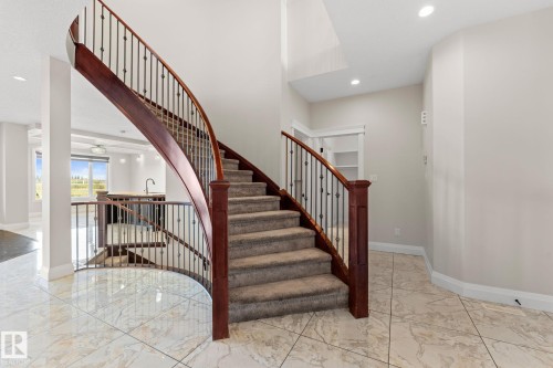 Curved staircase with wood-finish handrails and wrought iron spindles - 229 Albany Drive Nw, Edmonton, AB 