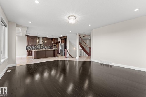 Dark wood-finish flooring, recessed lighting, chandelier, curved staircase, and a kitchen featuring dark wood cabinetry and stainless steel appliances - 229 Albany Drive Nw, Edmonton, AB 