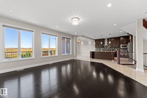 Expansive room with dark wood-finish flooring, recessed lighting, and a modern chandelier - 229 Albany Drive Nw, Edmonton, AB 