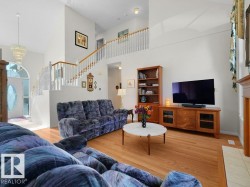 High ceilings, wood-finish flooring, two-story open staircase with wood handrails, and a transom window above the entry door - 