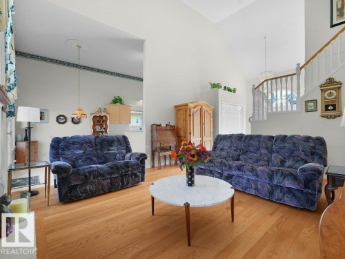 Vaulted ceilings highlight the bright interior, featuring wood-finish flooring and a white spindle staircase - 156 Phillips Row Nw, Edmonton, AB 