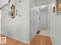 Wood-finish flooring and white painted walls, featuring a white spindle staircase with wood handrails - 