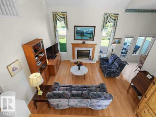 Vaulted ceiling, wood-finish flooring, fireplace with wood mantel, French doors, multiple windows - 156 Phillips Row Nw, Edmonton, AB 