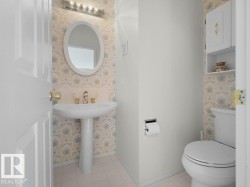 Main floor 2 pce. Pedestal sink with brass-finish faucet, overhead vanity lighting, and wall-mounted cabinetry - 