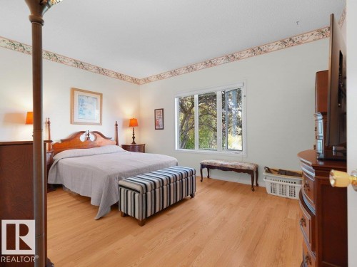 Located on the main floor. Wood-finish flooring throughout, white walls with decorative border, and a large window providing natural light - 156 Phillips Row Nw, Edmonton, AB 