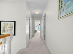 Carpeted hallway with white walls, multiple doorways, and a flush mount ceiling light - 