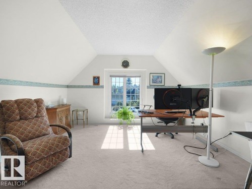 Sloped ceilings, window with grid panes, textured ceiling, light-toned carpeting, and a wood-finish desk - 156 Phillips Row Nw, Edmonton, AB 
