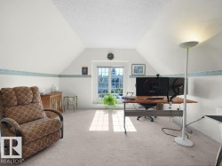 Sloped ceilings, window with grid panes, textured ceiling, light-toned carpeting, and a wood-finish desk - 