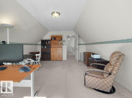 Carpeted room with sloped ceilings, ceiling-mounted light fixture, and a white paneled door - 156 Phillips Row Nw, Edmonton, AB 