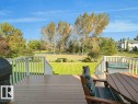 Expansive rear deck with railing system, offering broad views of the substantial lawn area and mature trees - 156 Phillips Row Nw, Edmonton, AB 