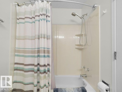 Bathtub with integrated shower, wall-mounted showerhead, and chrome fixtures - 156 Phillips Row Nw, Edmonton, AB 