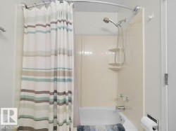 Bathtub with integrated shower, wall-mounted showerhead, and chrome fixtures - 