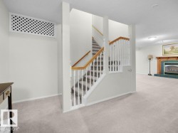 Carpeted flooring, white balusters, wood handrail, recessed lighting, and a fireplace with a wood mantle - 