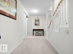 Wall-to-wall carpeting, staircase with wood handrail, white balusters, and a built-in closet with bifold doors - 