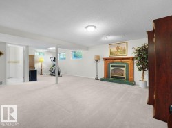 Carpeted lower-level room with a fireplace featuring a wood mantel and green tile surround - 