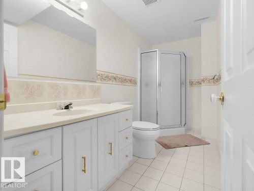 White cabinet vanity with gold-tone hardware, an integrated sink, and a framed mirror - 156 Phillips Row Nw, Edmonton, AB 