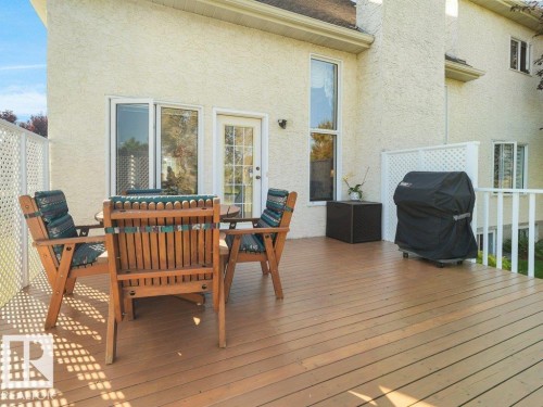 Expansive wood-finish deck with white lattice privacy screens, a white railing, and a rear exterior door - 156 Phillips Row Nw, Edmonton, AB 