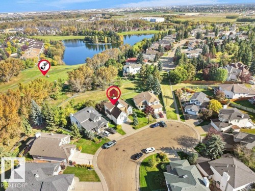Aerial perspective showcasing a residential area with varied housing styles, mature trees, and a prominent water body - 156 Phillips Row Nw, Edmonton, AB 