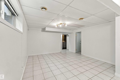 Expansive room with white tile flooring, drop ceiling, and a large window - 3524 Mclean Crescent Sw, Edmonton, AB 