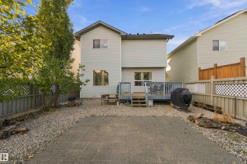 Rear exterior featuring light-colored siding, a multi-level deck, and a stone patio - 3524 Mclean Crescent Sw, Edmonton, AB 