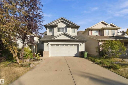Two-story residence with a front-facing attached garage, light-toned siding, and a dark shingle roof - 3524 Mclean Crescent Sw, Edmonton, AB 