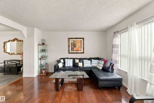 Warm wood-finish flooring throughout, bright white walls, and vertical blinds on the window - 3524 Mclean Crescent Sw, Edmonton, AB 