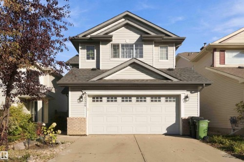 Two-story residence featuring light-colored siding, a dark shingle roof, and a two-car garage with transom windows - 3524 Mclean Crescent Sw, Edmonton, AB 
