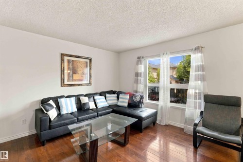 Expansive window with natural light, wood-finish flooring, and neutral wall tones - 3524 Mclean Crescent Sw, Edmonton, AB 