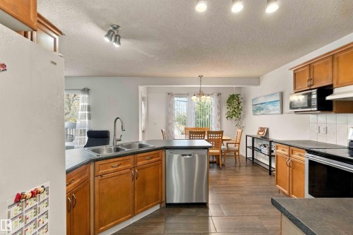 Kitchen featuring wood cabinetry, stainless steel appliances, and dark countertops - 3524 Mclean Crescent Sw, Edmonton, AB 