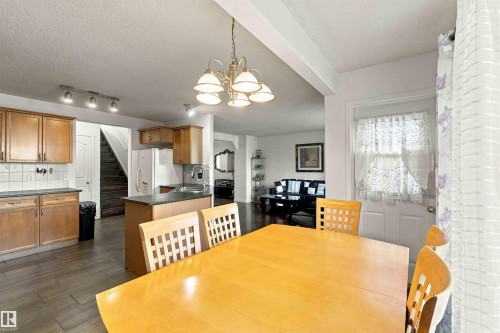 Kitchen featuring wood-finish cabinetry, dark countertops, and a tiled backsplash - 3524 Mclean Crescent Sw, Edmonton, AB 
