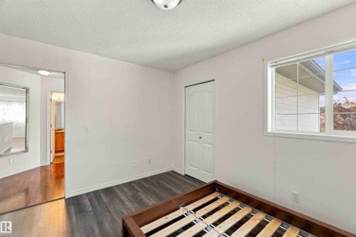 Neutral wall color with a textured ceiling, dark wood-finish flooring, and a white framed window - 3524 Mclean Crescent Sw, Edmonton, AB 