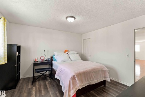 Bedroom with wood-finish flooring, a flush-mount ceiling light, and a white paneled door - 3524 Mclean Crescent Sw, Edmonton, AB 
