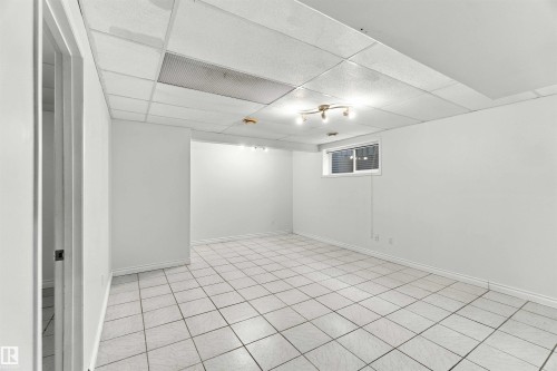 White ceramic tile flooring, drop ceiling with integrated lighting, recessed window, and white painted walls - 3524 Mclean Crescent Sw, Edmonton, AB 