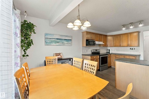 Kitchen featuring wood-finish cabinetry, stainless steel appliances, dark countertops, and a white subway tile backsplash - 3524 Mclean Crescent Sw, Edmonton, AB 