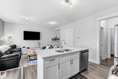 Kitchen island with an undermount double-basin sink, stainless-steel faucet, and a stainless-steel dishwasher - #15 4835 Wright Dr Sw, Edmonton, AB 