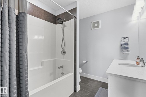 Integrated bathtub and shower with a tile surround, single vanity with an integrated sink, and tile flooring - #15 4835 Wright Dr Sw, Edmonton, AB 