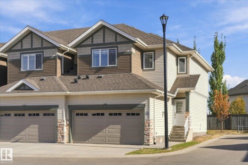 Multi-level facade with mixed siding, dual garage doors, exterior lighting, and a prominent entry staircase - #15 4835 Wright Dr Sw, Edmonton, AB 