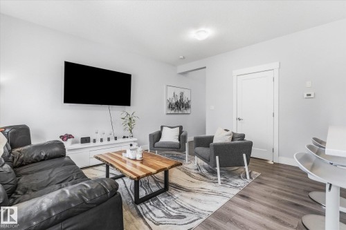 Wood-finish flooring throughout, white trim and door frames, recessed lighting, and a built-in media console - #15 4835 Wright Dr Sw, Edmonton, AB 
