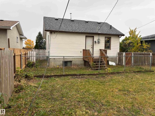 Rear exterior featuring vinyl siding, shingle roof, and a wood-finish deck with stairs - 7623 130 Avenue Nw, Edmonton, AB 