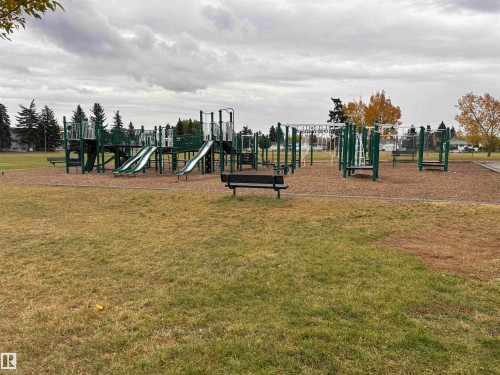 Community park with playground structures, multiple slides, monkey bars, and benches - 7623 130 Avenue Nw, Edmonton, AB 