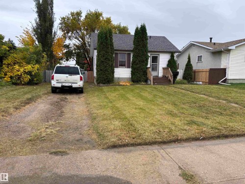 White siding exterior with a dark shingled roof, featuring a front lawn and a gravel driveway - 7623 130 Avenue Nw, Edmonton, AB 