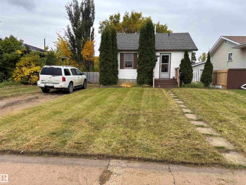 White siding exterior with a dark shingled roof, featuring a front porch with dark-stained wood steps, and a stone walkway - 7623 130 Avenue Nw, Edmonton, AB 