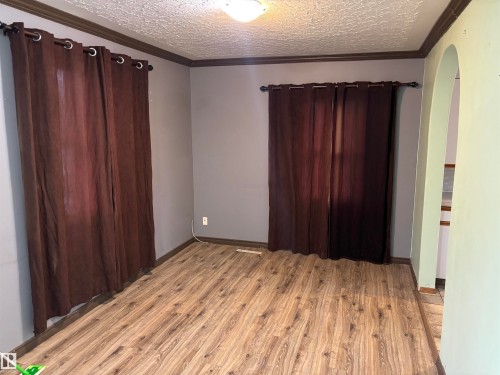 Wood-finish flooring throughout, crown molding, and an arched doorway - 7623 130 Avenue Nw, Edmonton, AB 