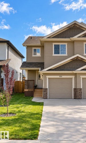 Two-story exterior with neutral siding, stone accents, attached garage, and concrete driveway - 3011 17 Avenue Nw, Edmonton, AB 